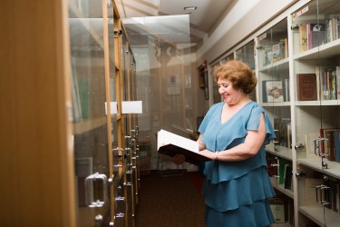 A woman standing in a hallway reading a book
